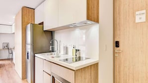 Una cocina moderna con armarios blancos, un refrigerador de acero inoxidable y un lavamanos empotrado.
