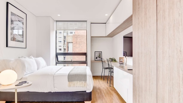 Un dormitorio moderno con cama, mesita de noche y vistas a la ciudad.