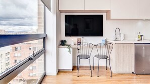 Eine moderne Küche mit großem Fenster, Flachbildfernseher und einem kompakten Kühlschrank.