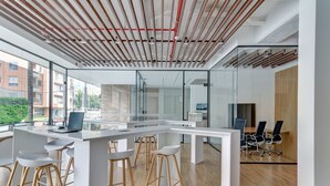 A modern office space with a white desk, bar stools, a laptop, and a conference area with chairs. - w Signature Loft in the Heart of Bogot (Bogotá)