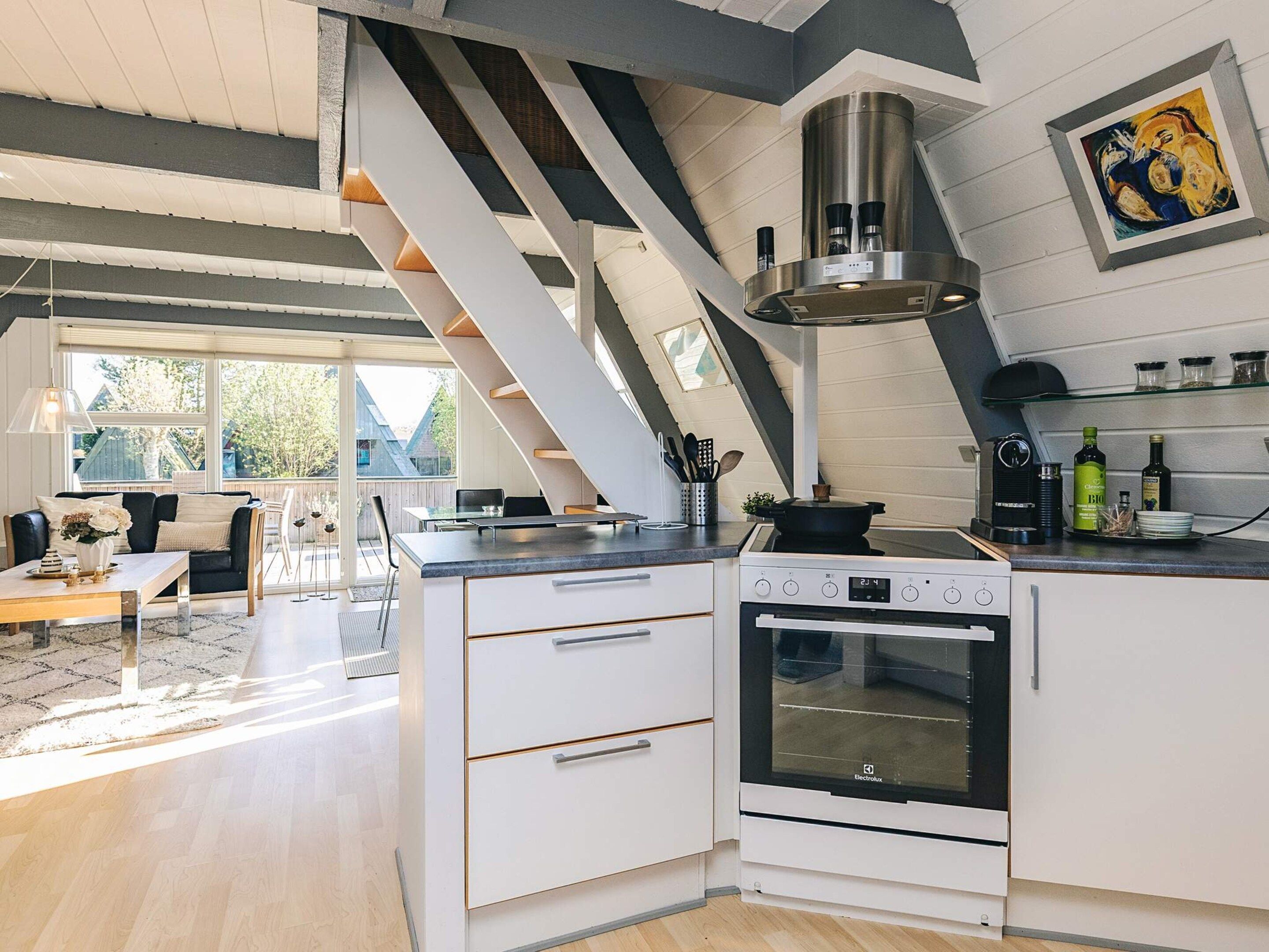 A modern kitchen with a built-in oven, a stove, and a large window overlooking a deck area.