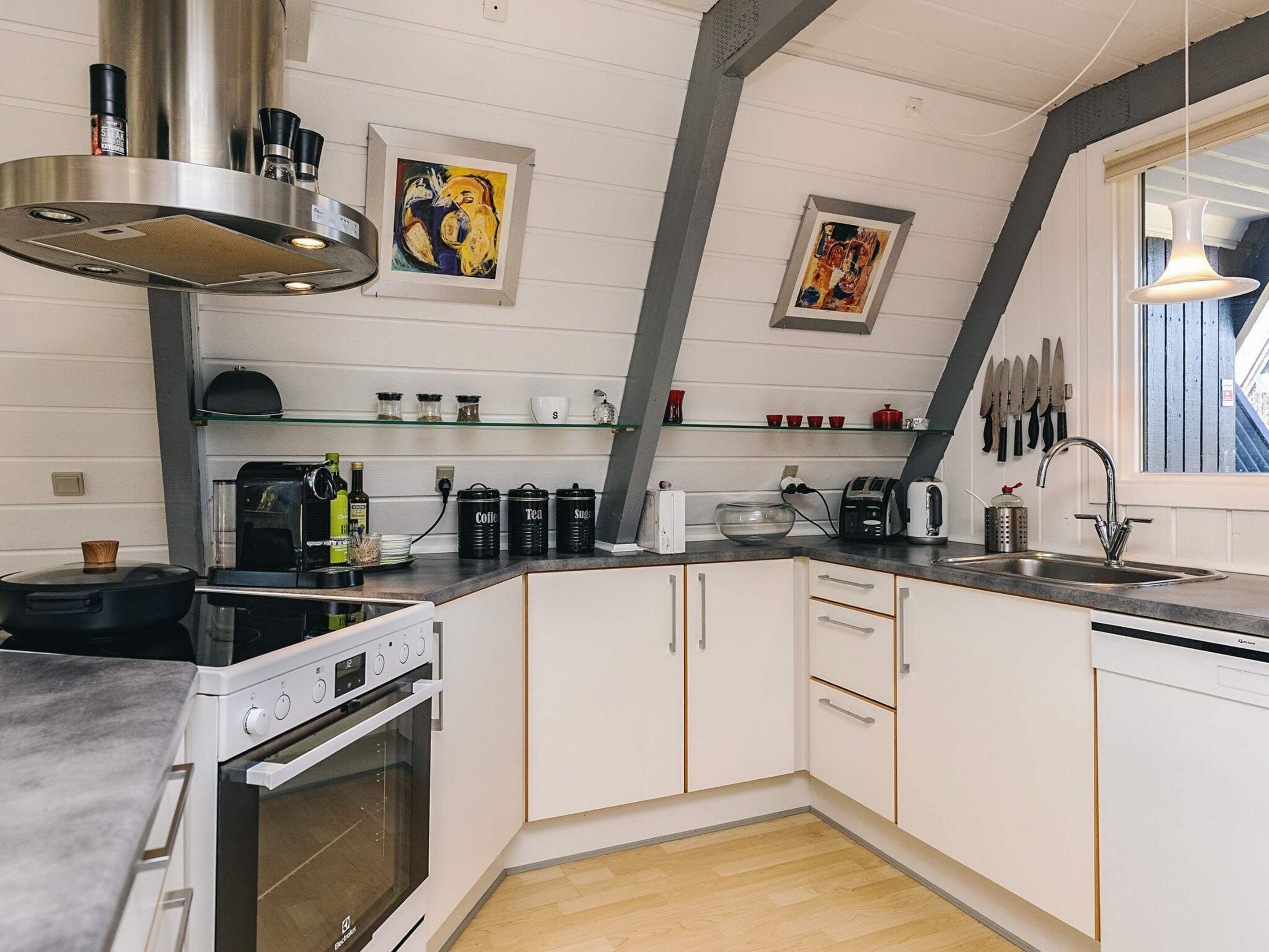 A modern kitchen with white cabinetry, a built-in oven, a coffee machine, and a window with a view.