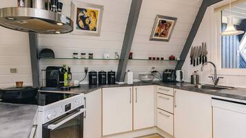 A modern kitchen with white cabinetry, a built-in oven, a coffee machine, and a window with a view.
