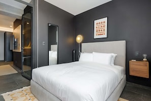A modern bedroom with a large bed, a glass shower enclosure, a bedside table with a lamp, and a framed picture on the wall. - w Nest-style 1BR in Lively Tabacalera (Mexico City)