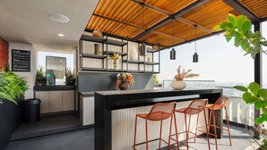 A modern kitchen with a bar area, wooden ceiling, and potted plants. - w Nest-style 1BR in Lively Tabacalera (Mexico City)