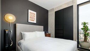 A modern hotel room with a large bed, a standing heater, a framed picture on the wall, and a view of the city through a window. - w Nest-style 1BR in Lively Tabacalera (Mexico City)