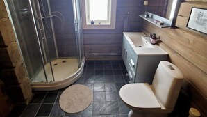 Une salle de bain équipée d’une douche, de toilettes, d’un lavabo et d’une petite fenêtre.
