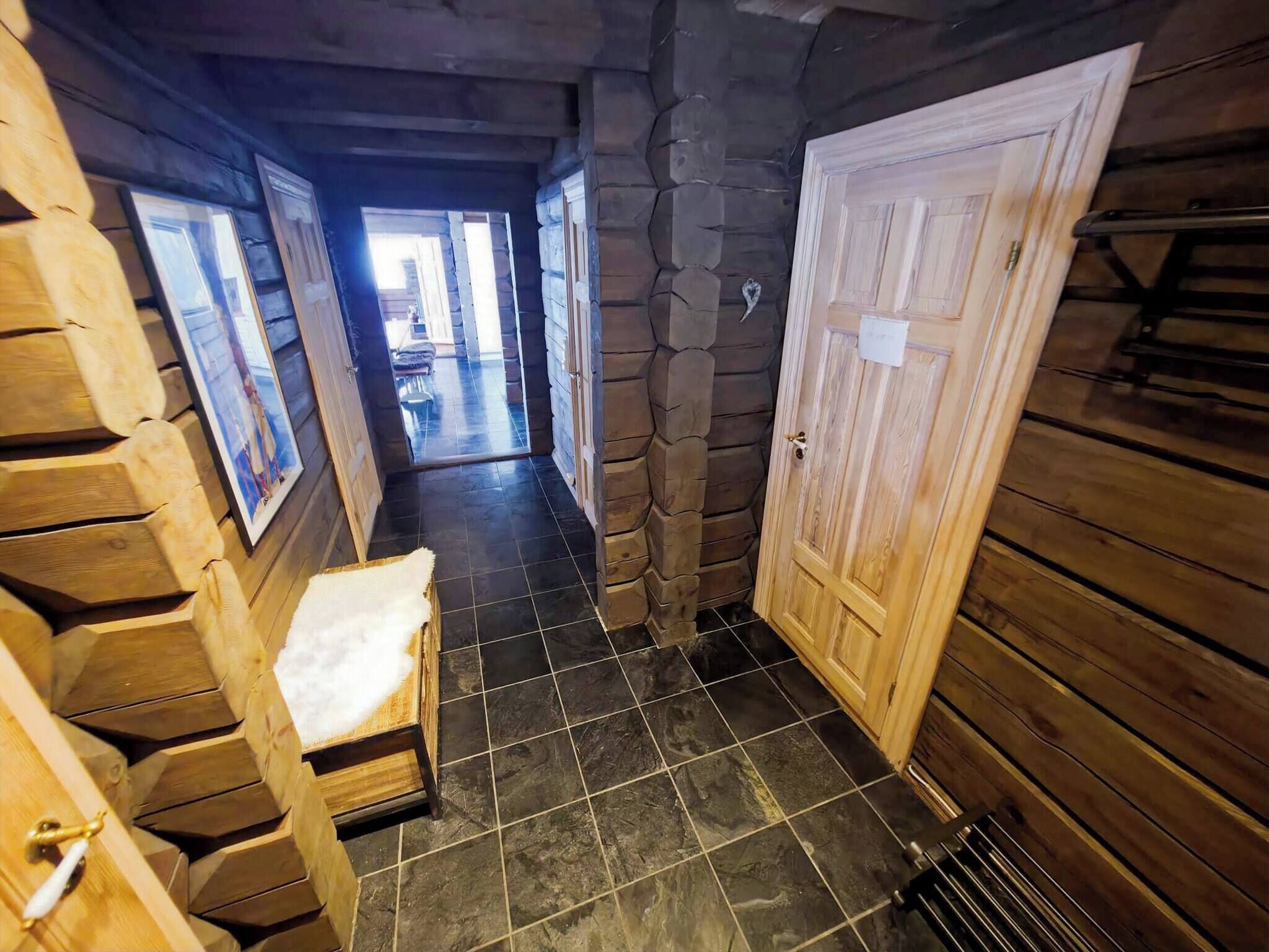 A wooden interior hallway with a bench, a door, and a tiled floor.