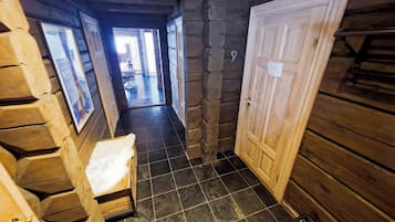 A wooden interior hallway with a bench, a door, and a tiled floor.