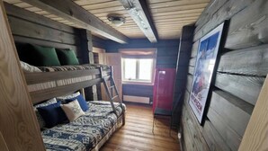 L'intérieur d'une cabine comprenant un lit superposé, un canapé, une échelle et une affiche accrochée au mur.