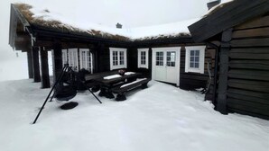 Une cabane en bois avec un toit de chaume, un banc en bois et un sol recouvert de neige.