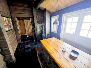 A log cabin interior with a wooden table, a stone fireplace, and a door labeled 'TRYSIL'.