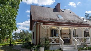 Une maison avec un porche, une cheminée et un jardin.