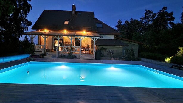 Une maison avec une piscine, un patio couvert et un garage.