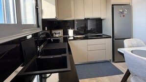 A modern kitchen with a black countertop, stainless steel appliances, and light-colored cabinets. - Cozy Family Villa close to the beach! (Vlora)