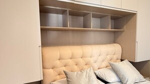 A bedroom with a tufted headboard, a bed with a quilted bedspread, and built-in shelving above the bed. - Cozy Family Villa close to the beach! (Vlora)