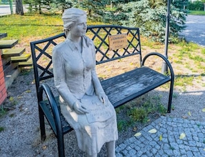 A statue of a seated woman on a bench with a plaque. - 4-person Room, Sauna, Masuria (Ruciane-Nida)