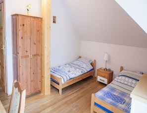 A small, single-room accommodation with a wooden wardrobe, a bed with a patterned bedspread, a bedside table with a lamp, and a small chair. - 4-person Room, Sauna, Masuria (Ruciane-Nida)