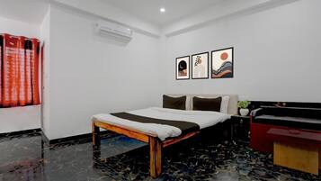 Habitación de hotel con cama, mesita de noche, cómoda roja y tres obras de arte enmarcadas en la pared.