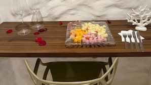 Una mesa de comedor con un plato de comida, copas de vino y una silla blanca.