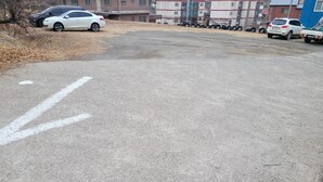 A parking lot with cars and a building in the background.
