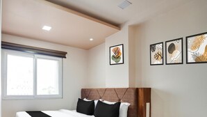 Ein Schlafzimmer mit einem hölzernen Bett, einem Fenster und gerahmten Kunstwerken an der Wand.