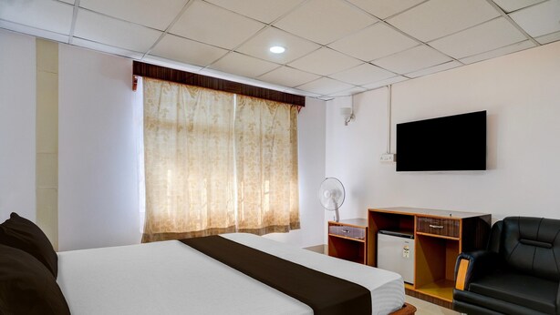 Une chambre d’hôtel comprenant un lit, un bureau avec un ventilateur, une télévision et un canapé.