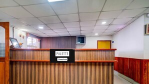Un comptoir d’accueil portant l’inscription « PALETTE », avec un panneau indiquant qu’il est entretenu par l’entreprise, un décor en panneaux de bois et une horloge au mur.