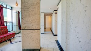 A hotel lobby with a marble column, red upholstered seating, and a view through a glass door. - Premiumhotel Seven Olive (Bengaluru)
