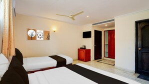 A hotel room with two beds, a ceiling fan, artwork on the wall, a TV, and a red cabinet. - Premiumhotel Seven Olive (Bengaluru)