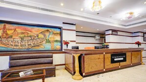 A reception area with a marble floor, a reception desk labeled 'TOWNHOUSE,' a bench, and a mural of a bridge. - Premiumhotel Seven Olive (Bengaluru)