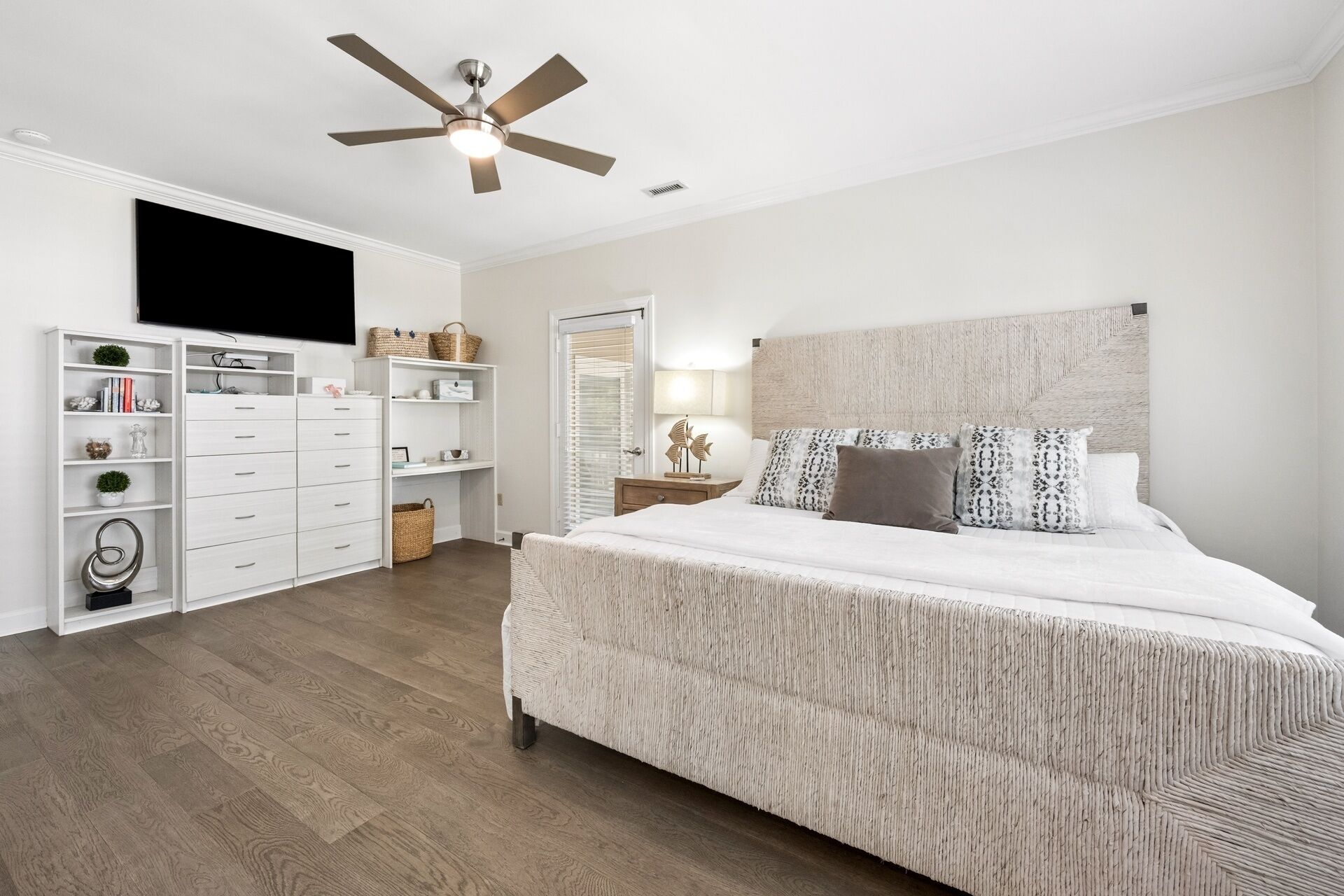 A bedroom with a bed, a ceiling fan, a TV, a bookshelf, and a nightstand.