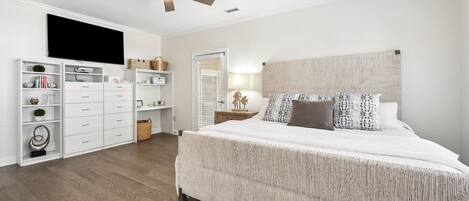 A bedroom with a bed, a ceiling fan, a TV, a bookshelf, and a nightstand.