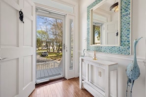 A hallway with a white door leading to a view of a parked vehicle and trees. - The Escape 3 Bedroom Villa (Georgetown)