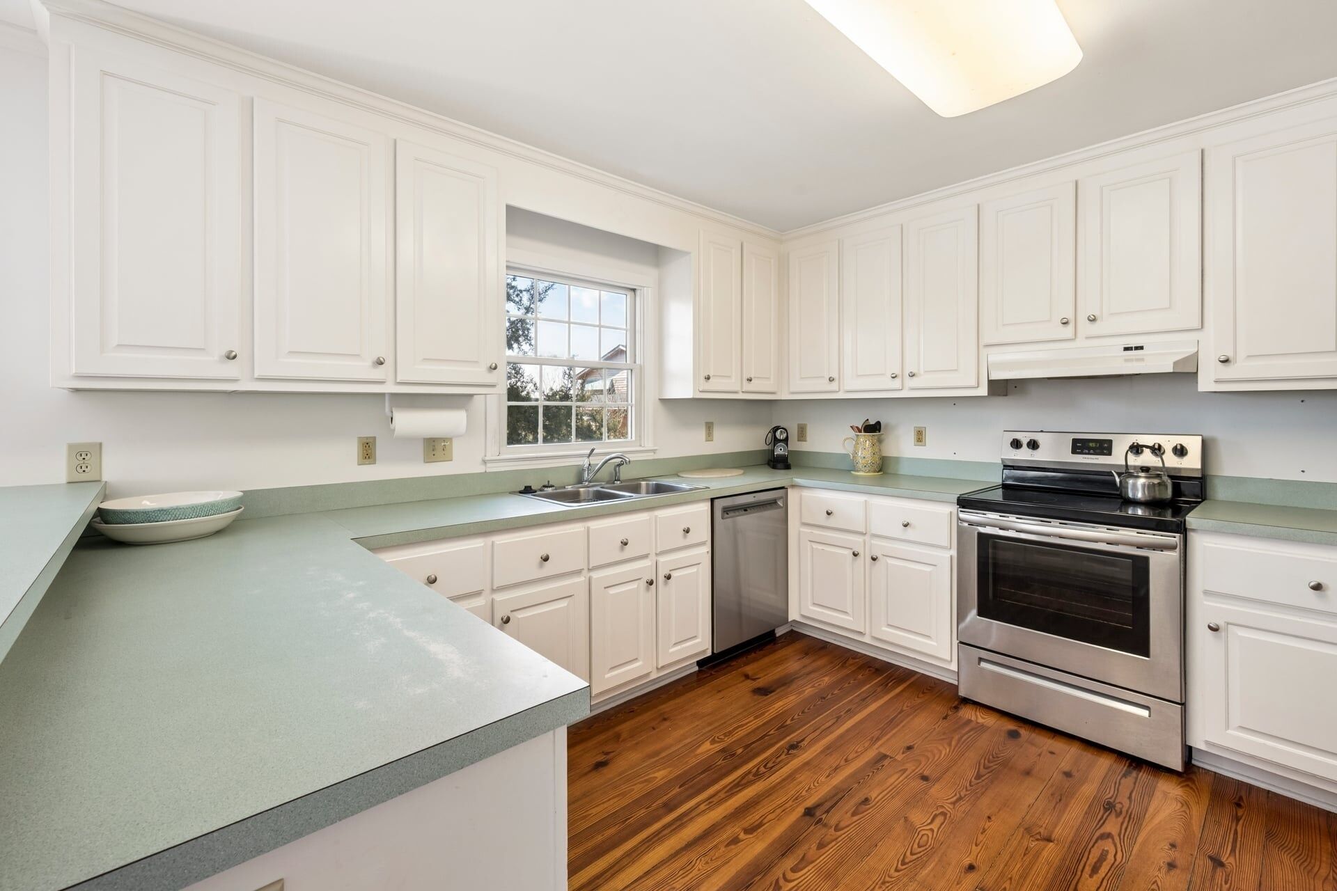 A kitchen with white cabinets, a stainless steel stove, and a dishwasher.