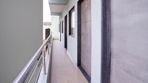 A hallway with a metal railing, doors, and a light-colored floor. - Hotel O Main Market Mahabaleshwar (Mahabaleshwar)