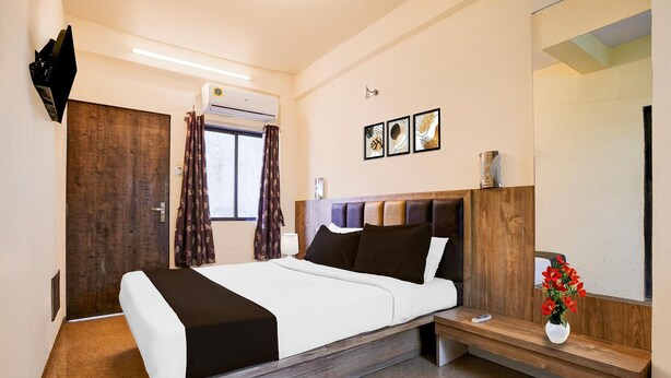 A modern hotel room with a bed, a bedside table, a mirror, and a window with curtains. - Hotel O Main Market Mahabaleshwar (Mahabaleshwar)