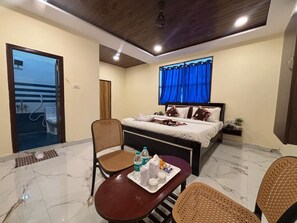 Habitación de hotel con cama, una mesa de comedor con sillas, un baño visible a través de una puerta abierta y un ventilador de techo.