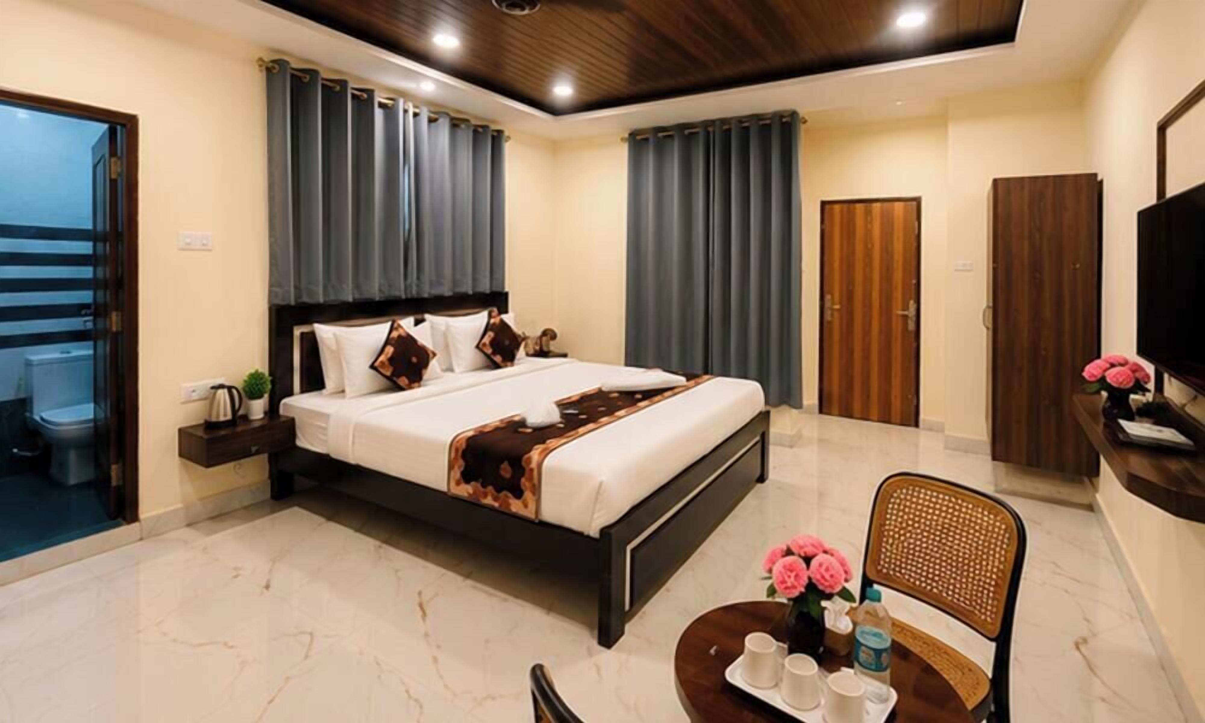 A hotel room with a bed, a desk, a chair, a TV, and a bathroom.