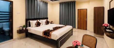 A hotel room with a bed, a desk, a chair, a TV, and a bathroom.
