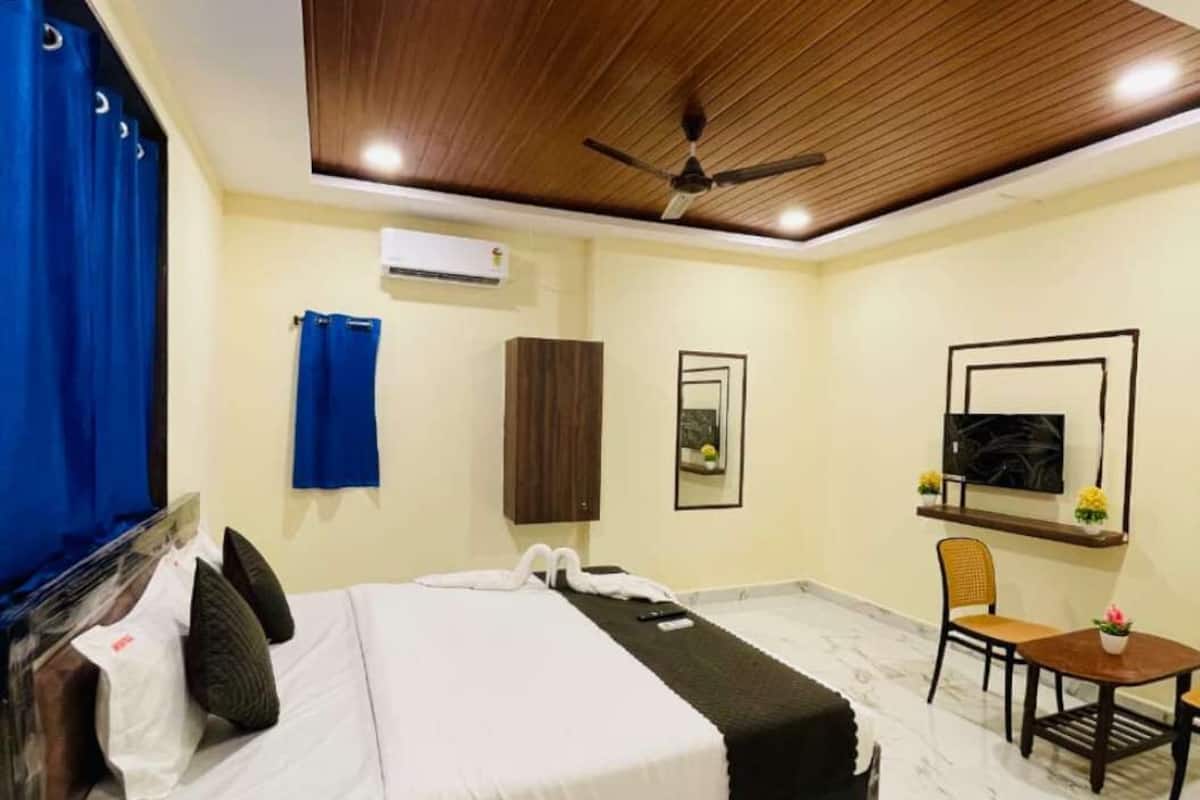 Una habitación de hotel con cama, escritorio, silla, ventilador de techo y aire acondicionado.