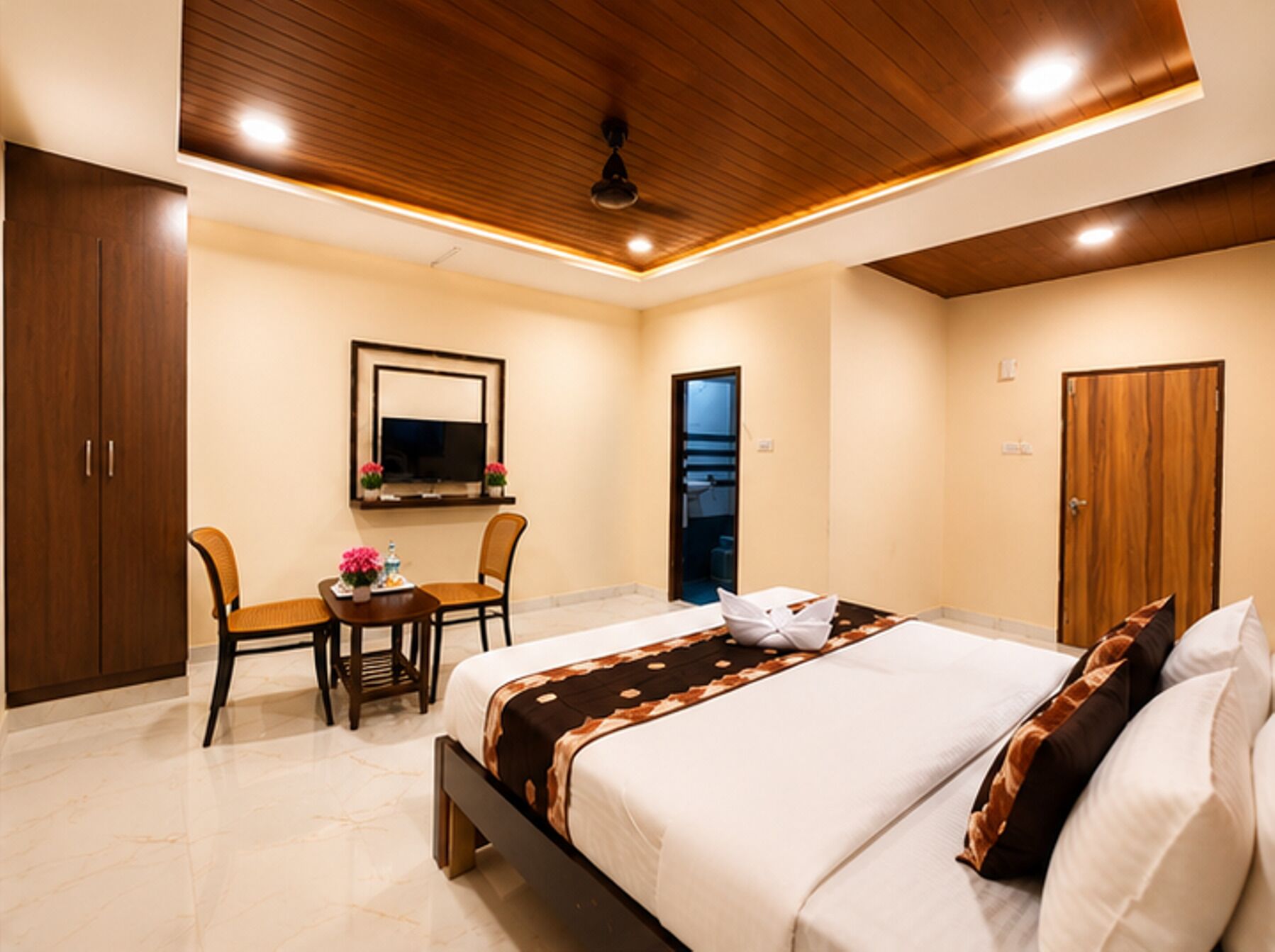 A hotel room with a bed, a desk, a chair, a wardrobe, and a mirror.
