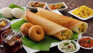 Un plato con idli, dosa y diferentes chutneys.