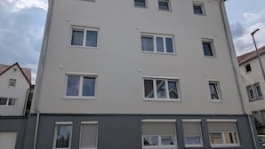 A multi-story building with several windows and a car parked in front.