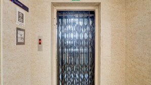 An elevator with a metal grille door, a green 'G' sign above it, and a 'No Visitors Allowed' sign on the wall. - Super Collection O Kphb (Hyderabad)