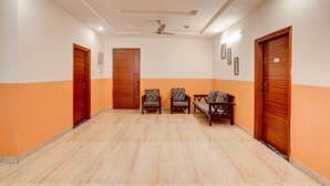 A spacious room with a tiled floor, a ceiling fan, and three wooden doors. - Super Collection O Kphb (Hyderabad)
