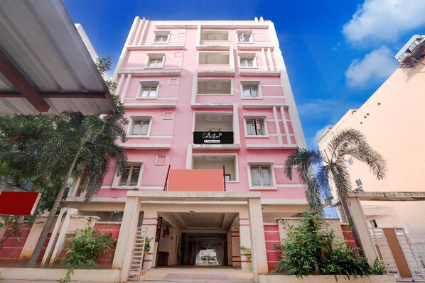 Un edifici rosa de diverses plantes amb una entrada central, balcons i un rètol que diu 'Collection'.