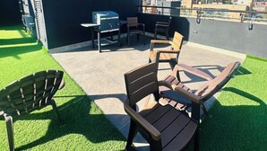 Une terrasse sur le toit, aménagée avec du mobilier d’extérieur, un barbecue et offrant une vue sur le panorama urbain.