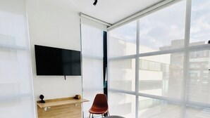 Une chambre moderne avec un grand lit, un bureau, une chaise et un téléviseur fixé au mur.