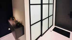 Une chambre moderne dotée d’une grande porte-fenêtre coulissante, d’un meuble de couleur sombre et d’un luminaire encastré au plafond.